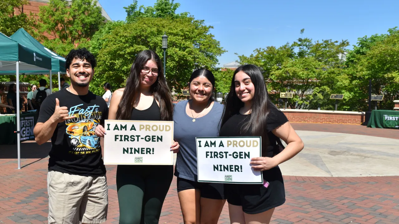 Students with a sign that says "Proud to be First"