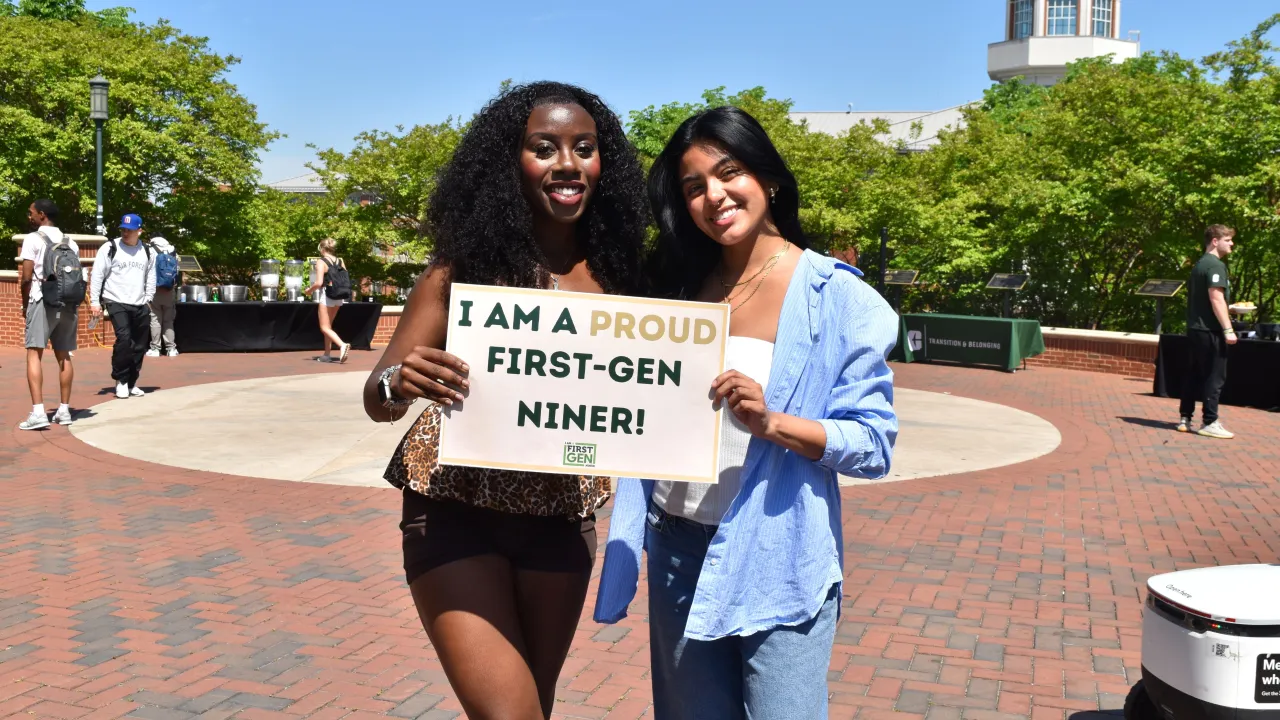 Students with a sign that says "Proud to be First"