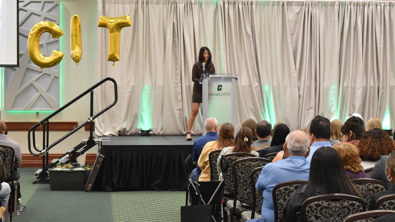 Student on stage giving a speech CLT next to her