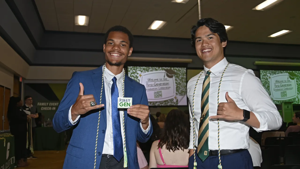 Two First-Gen Niners at First-Generation Graduation Celebration wearing their First-Gen honor cord and holding up pick-axes. 
