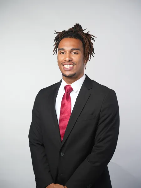 Person in a black suit with a red tie smiling 