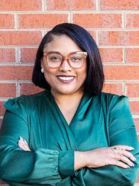 Person in green shirt and glasses posing for headshot.