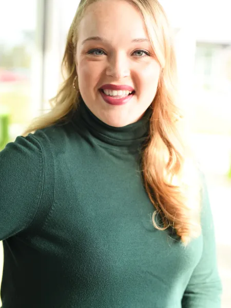 Person in green turtleneck posing for headshot.