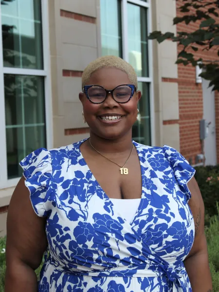 person smiling wearing glasses and a blue foral blouse 