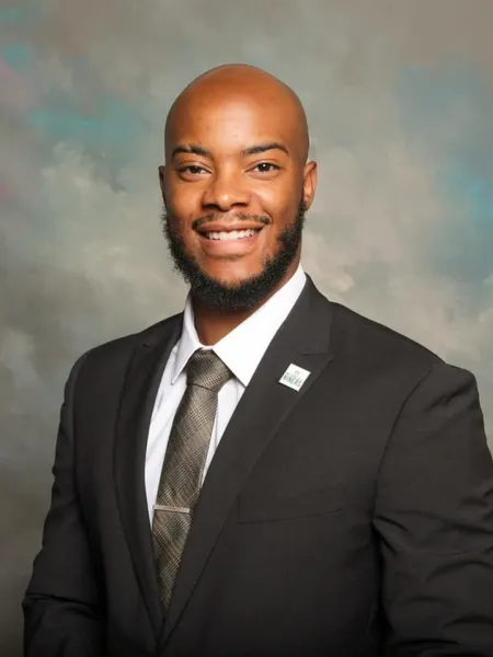 Man smiling in a suit against a pastel background