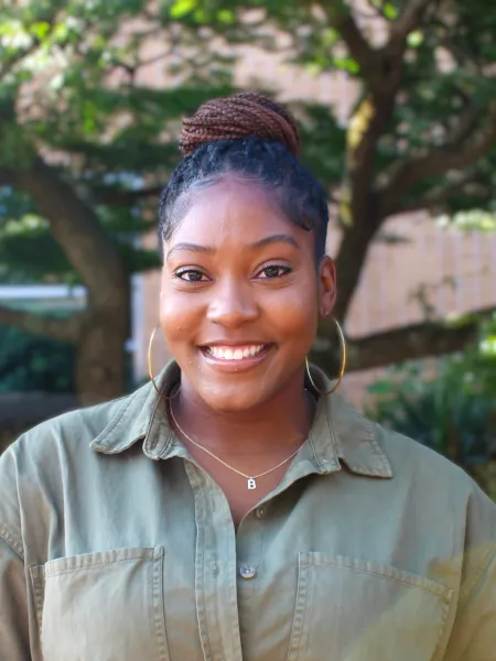 Person in green overshirt posing for headshot.