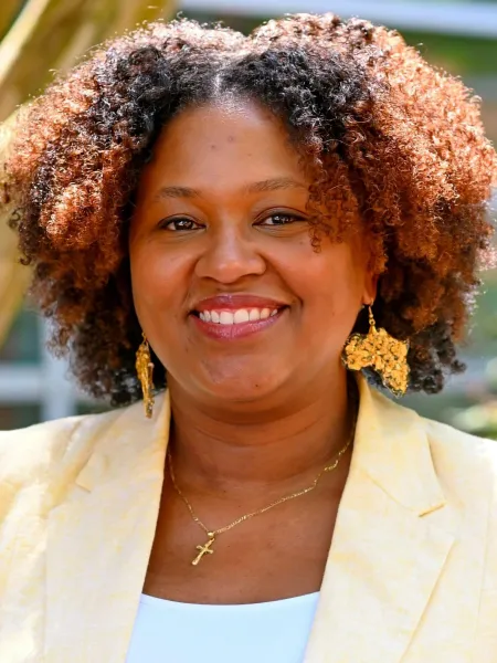 Person in gold jacket posing for headshot.