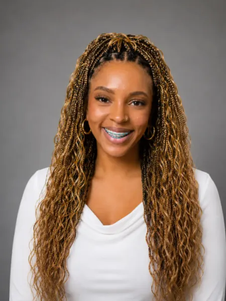 person in braids smiling wearing a white top