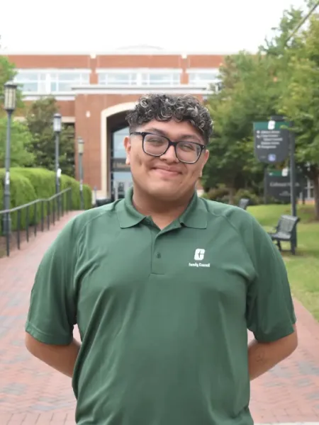 person wearing glasses and a green polo smiling