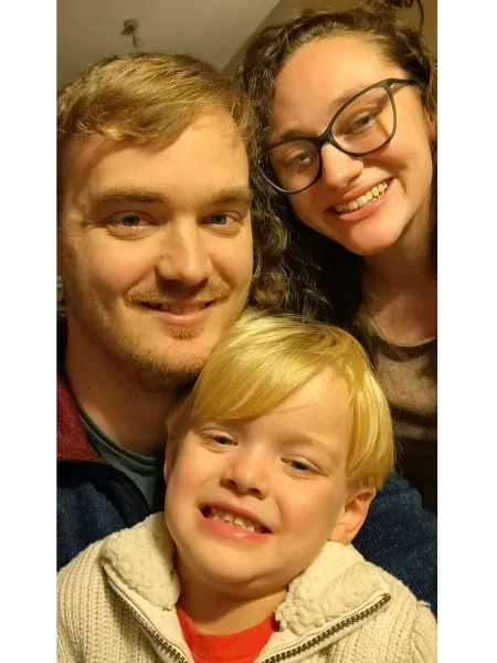 family of 3 smiling with small child in center