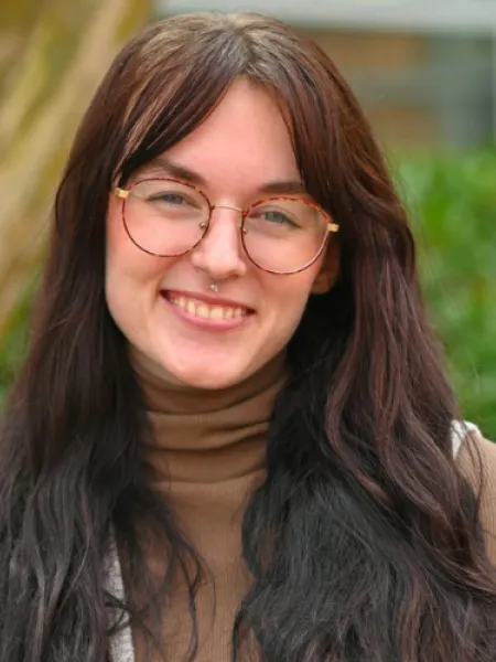 Person in glasses and brown turtleneck posing for headshot.