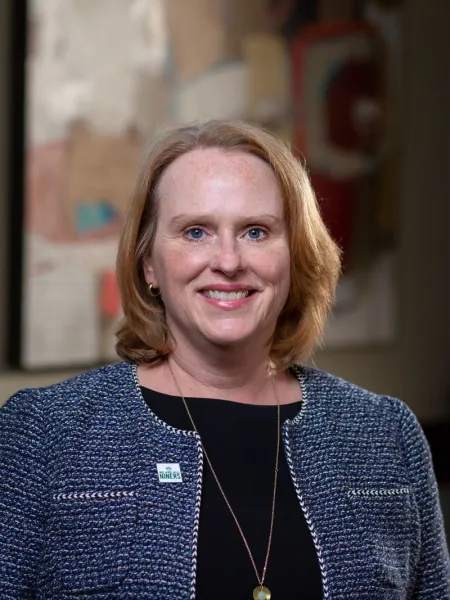 Woman wearing a blue blazer and a black blouse smiling. 