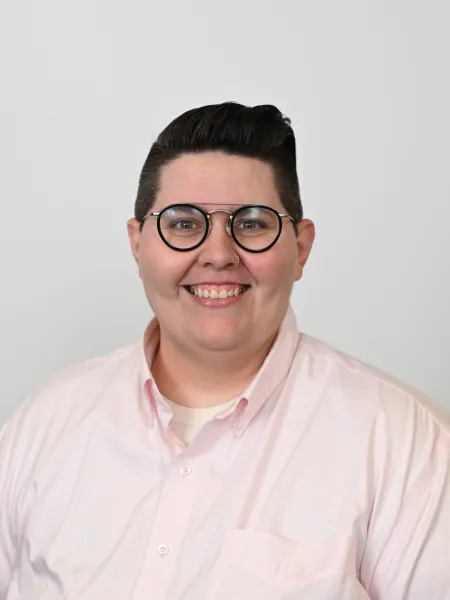 Person in pink shirt and glasses posing for headshot.