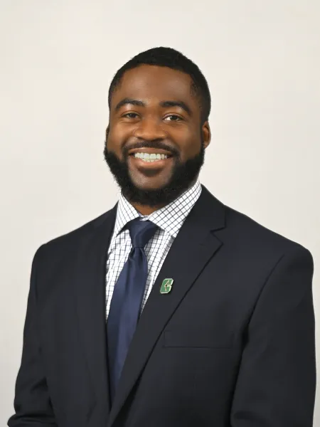 Person in blue suit, plaid shirt, and blue tie, posing for headshot.