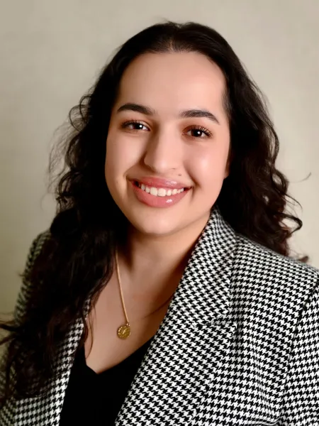 Person in black and white patterned blazer posing for headshot.