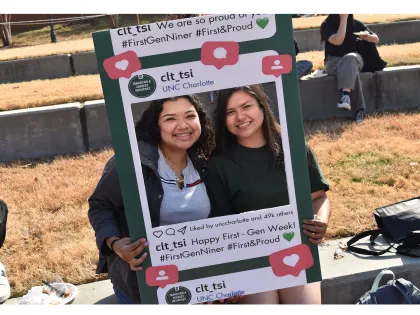 Two students holding photo frame smiling at first-gen cookout