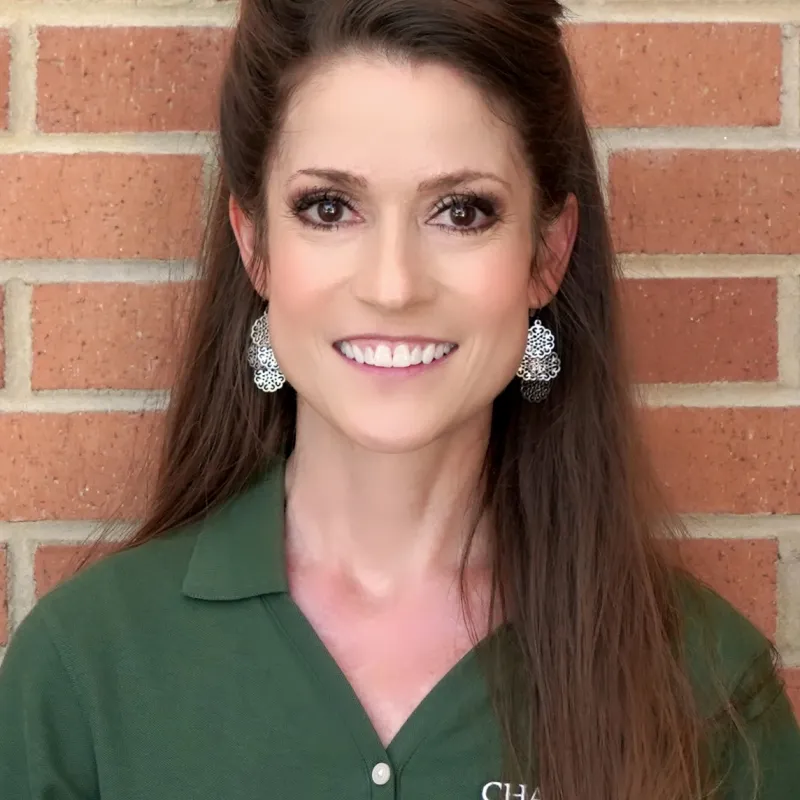 Woman wearing silver earrings and Charlotte polo and long brown hair