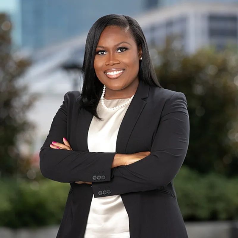 Woman with straight black hair, her arms folded wearing a black blazer 