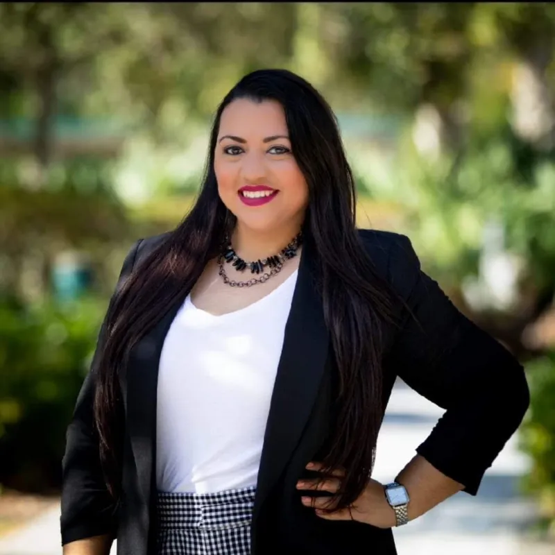 person with hand on hip and long black hair wearing a black blazer