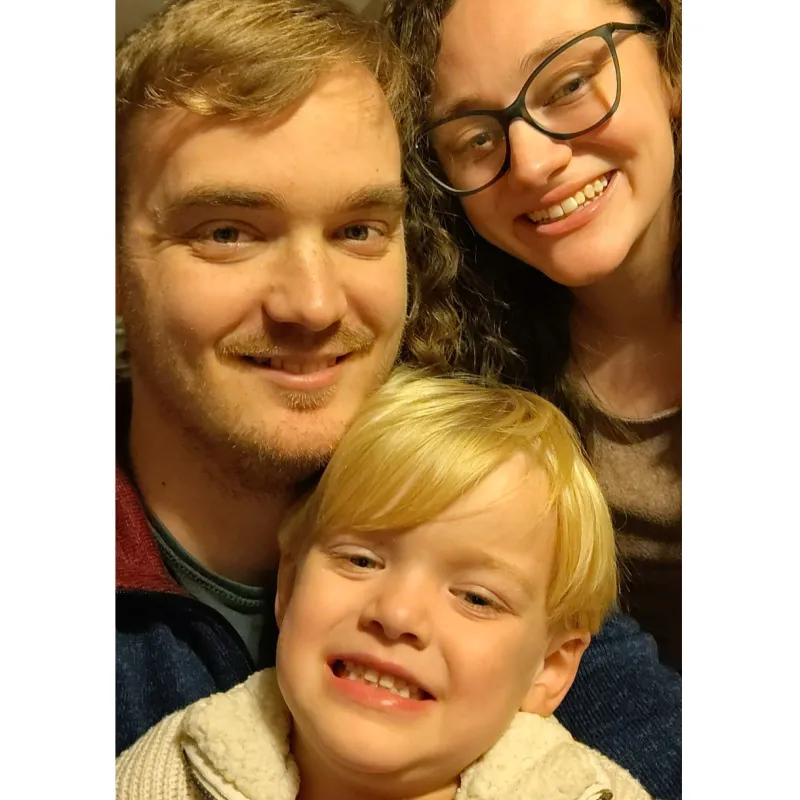 family of 3 smiling with small child in center