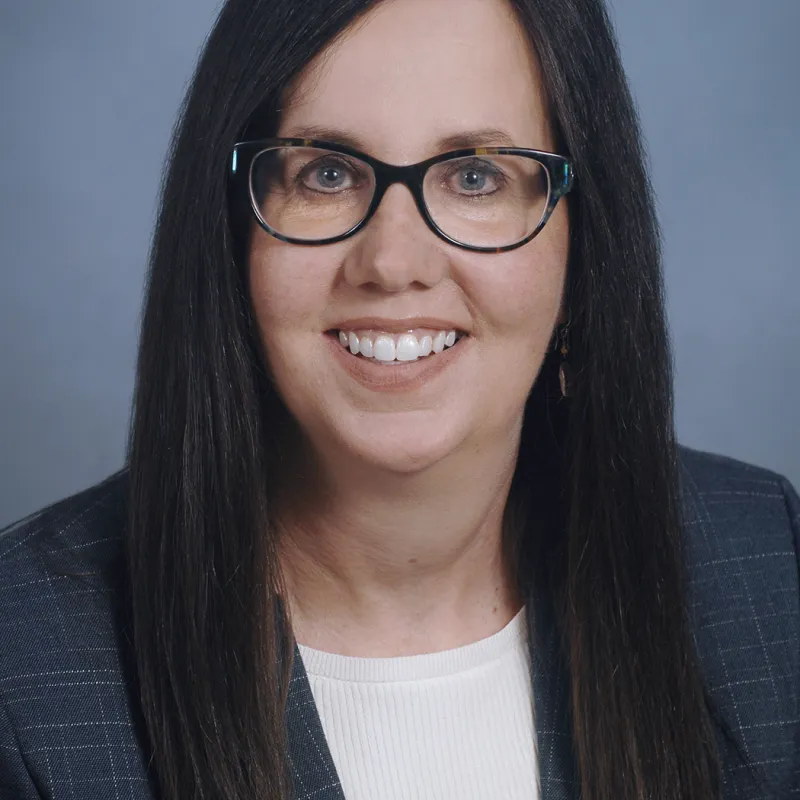 Woman wearing a blue blazer and glasses with long black hair 