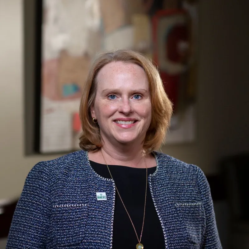 Woman wearing a blue blazer and a black blouse smiling. 