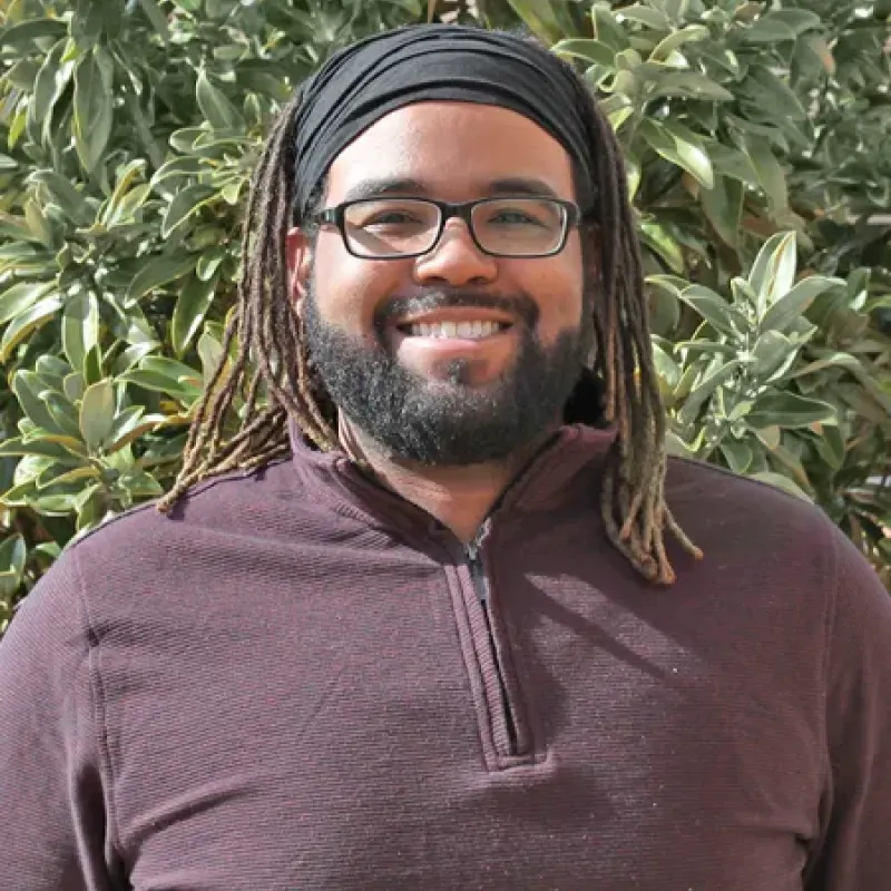 Person smiling wearing burgundy shirt with black headband  