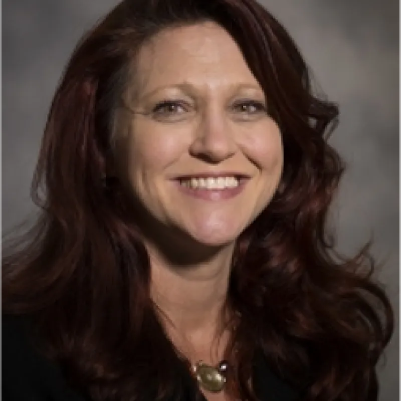 Woman smiling and looking at camera with curly brown hair 